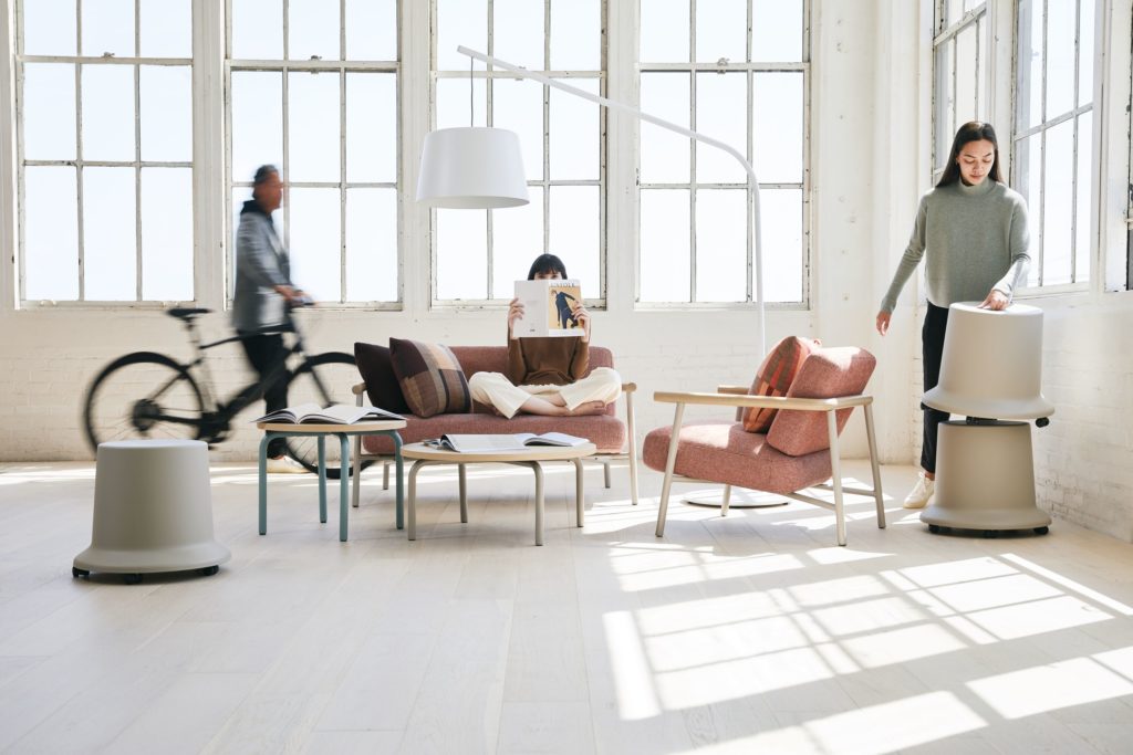 Teknion Routes loveseat and lounge chair with mobile stools and man with bicycle and two women