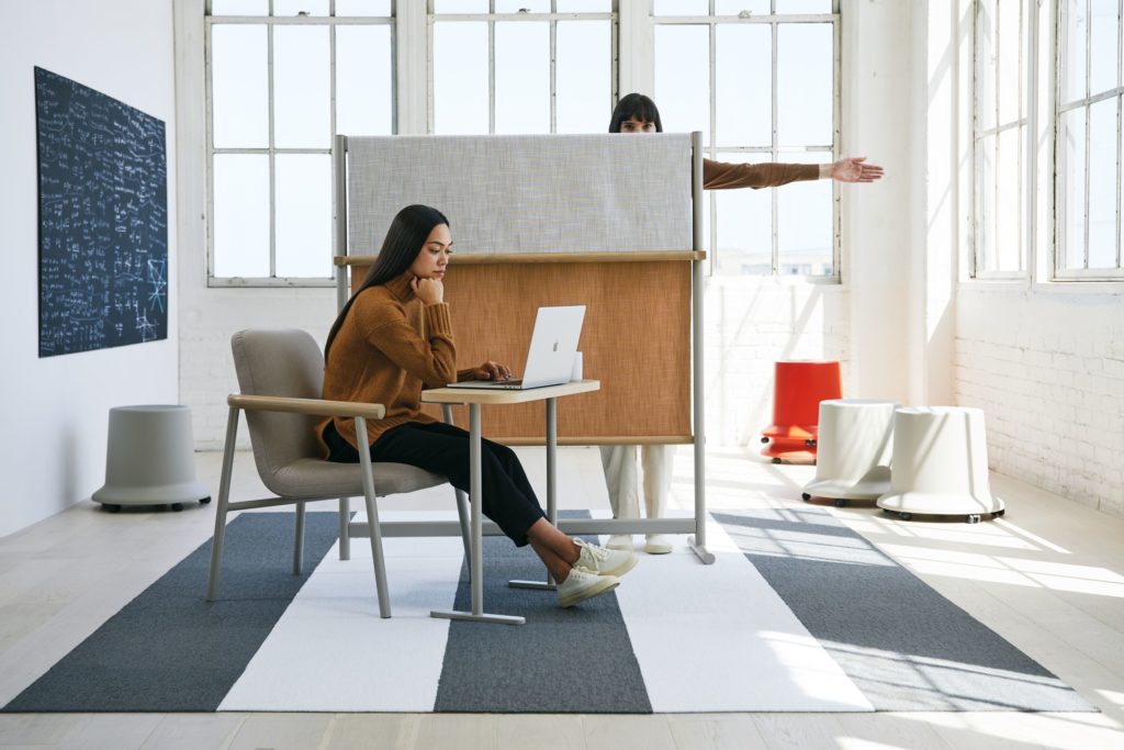 Teknion Routes woman working in chair with laptop table and other woman behind mobile partition