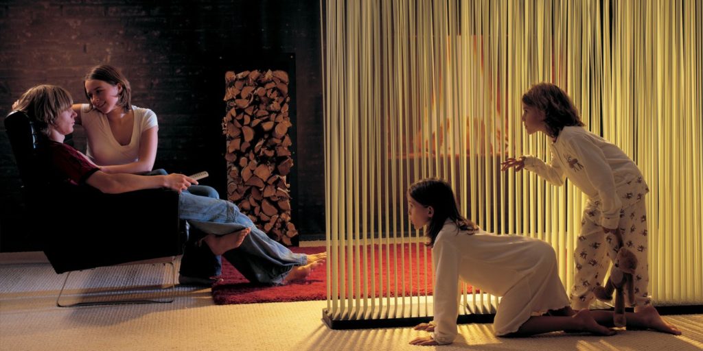Sticks in white in residential family room with husband and wife and children sneaking up behind partition