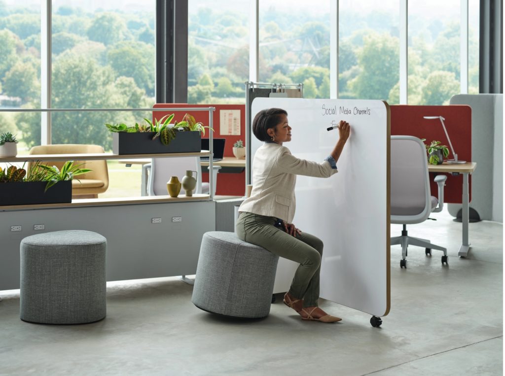 Mural breakout area with woman on ottoman writing on markerboard