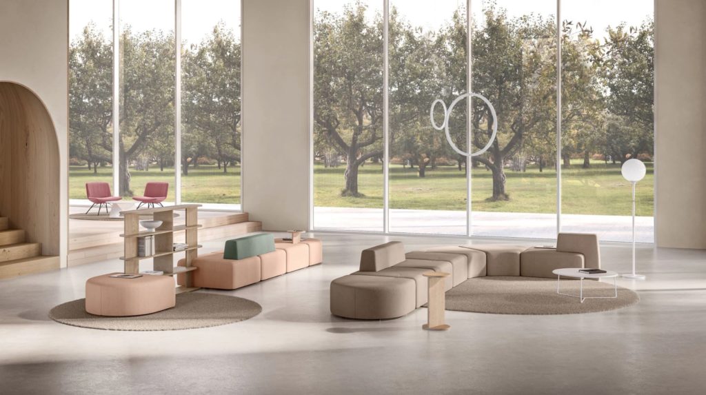 Open room with two large modular seating arrangements in front of large wiindow lookiing out on park