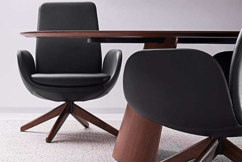 Front view of black Keilhauer lounge chair with partial view of a second chair and conference table