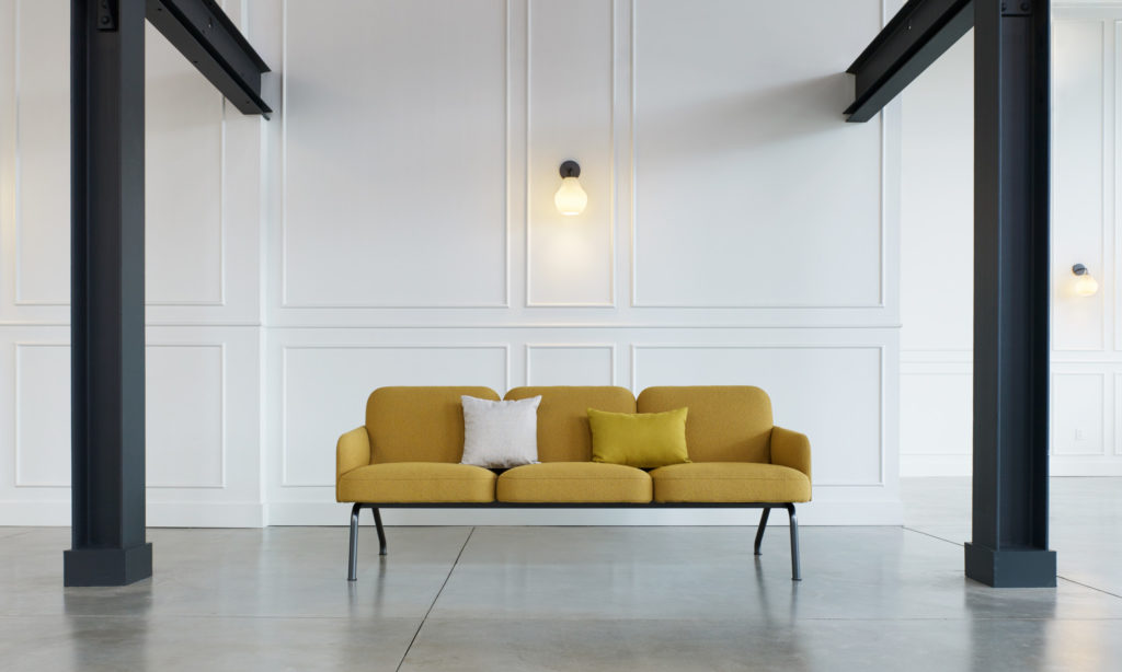 Nordic three-seater in yellow in room with large steel beams and posts