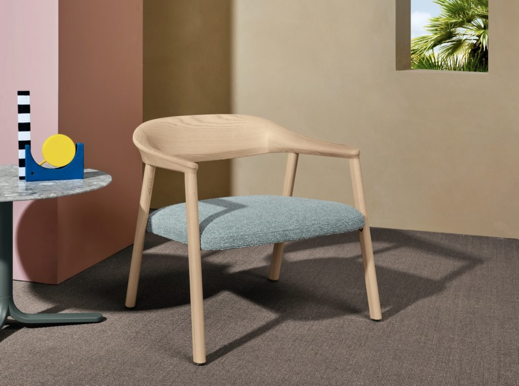 Héra lounge chair with green upholstery upholstery next to whimsical side table