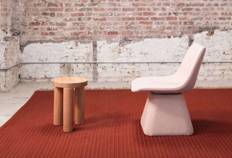 Volley chair in pink on red carpet with brick wall background