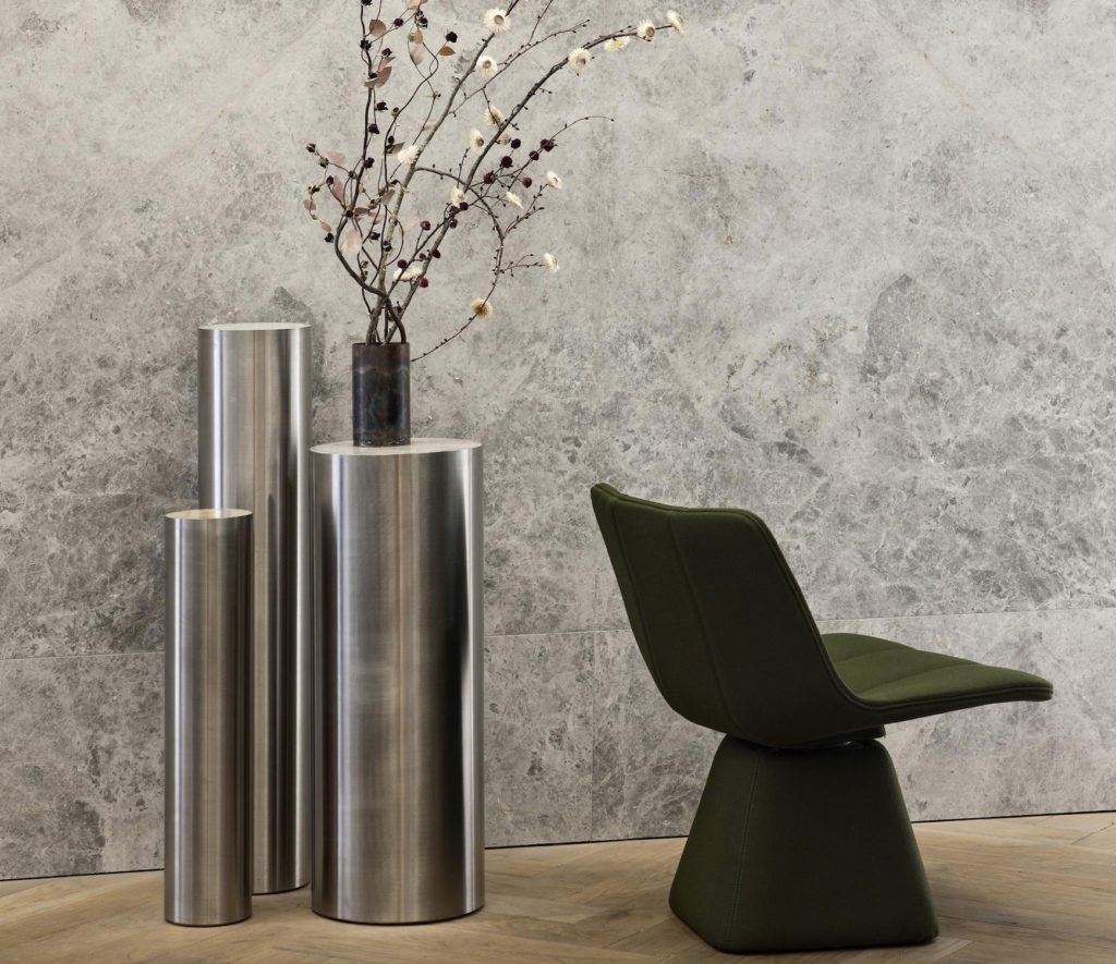 Volley chair in green velvet near steel cylindrical pedestal tables