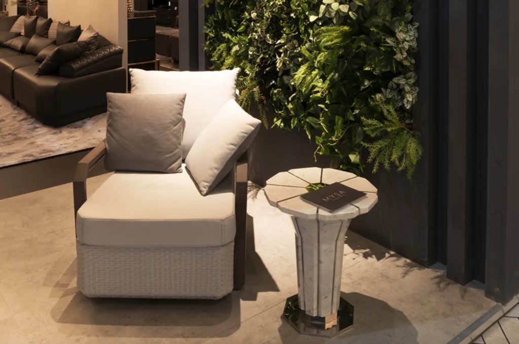 Luxxu marble table next to comfy chair as seen from slightly above with greenery in background
