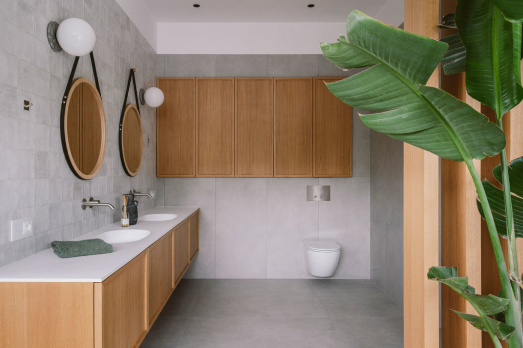 Giro sink with double basins finished in white in bathroom with natural wood cabinetry