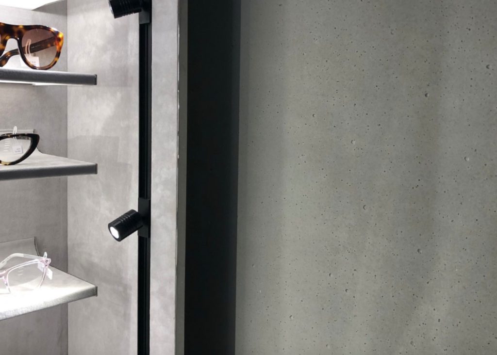 Concrete-like wall in closet or retail shop with glasses on shelves to the side