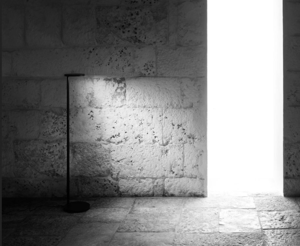 Floor lamp emitting light onto wall of rough stone