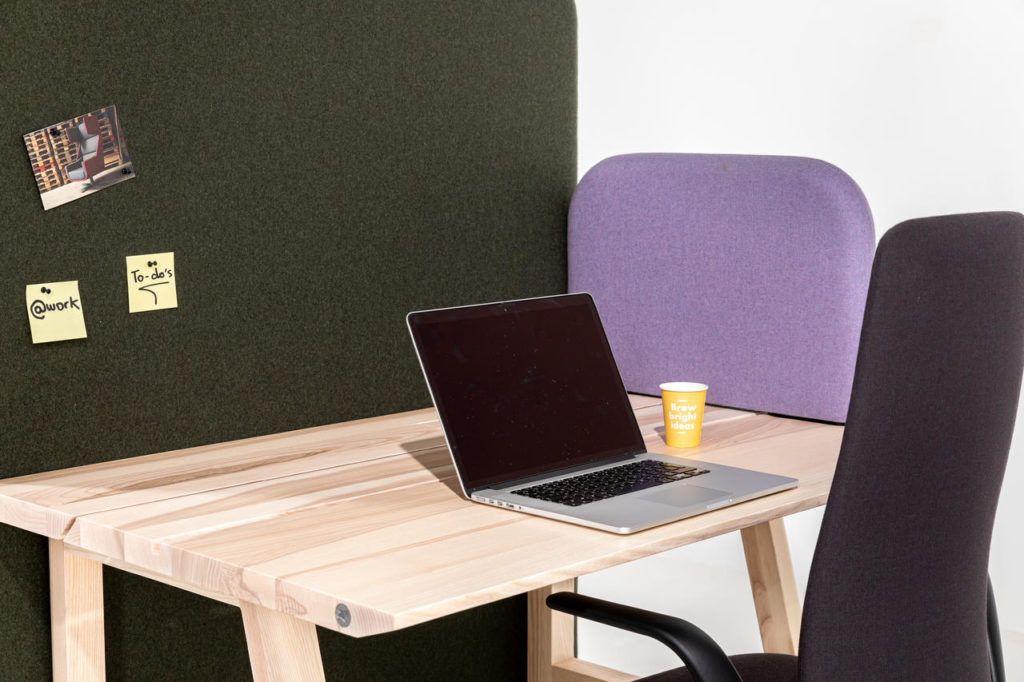 Close up of BuzziShield dividers, one in lavender and one darky gray on desk with open laptop