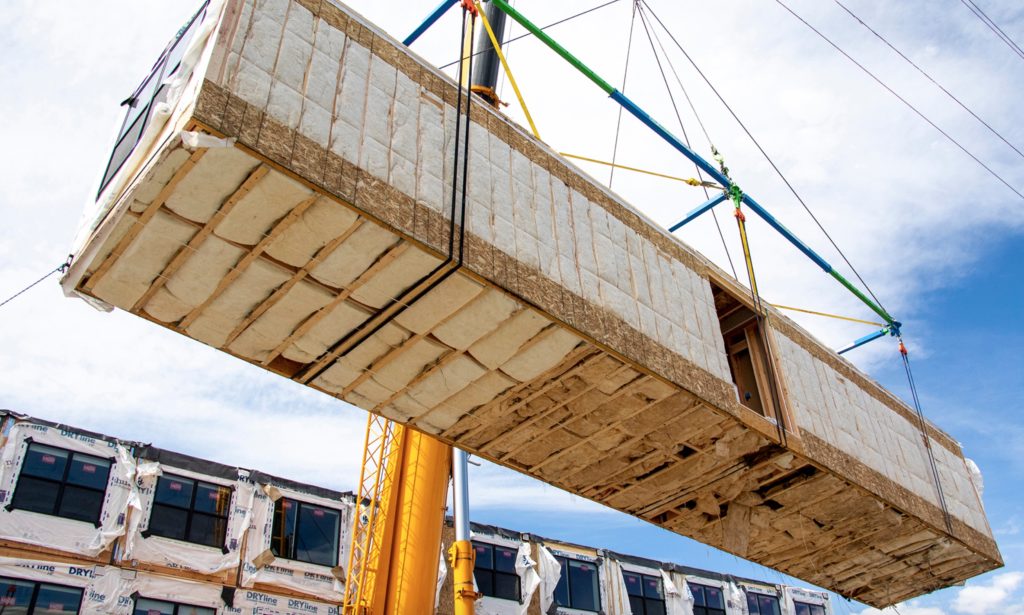 typical modular construction with a unit made of wood being craned into place