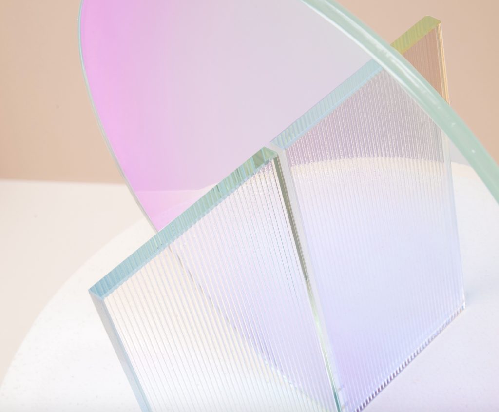 OmniDecor glass sculpture with round piece with pink highlights intersecting with square piece with faceted surface