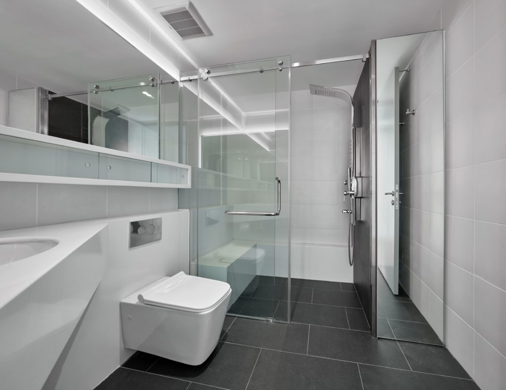 Cassette bathroom with black tile glass shower surround, white vanity and storage