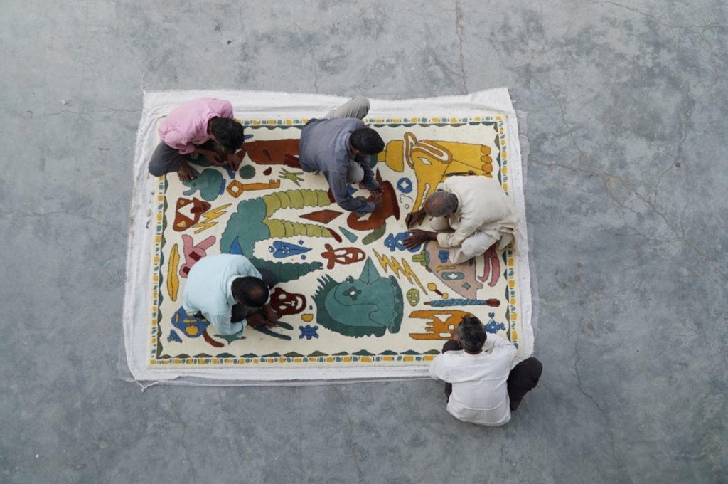 Troupe under construction with artisans sitting on rug