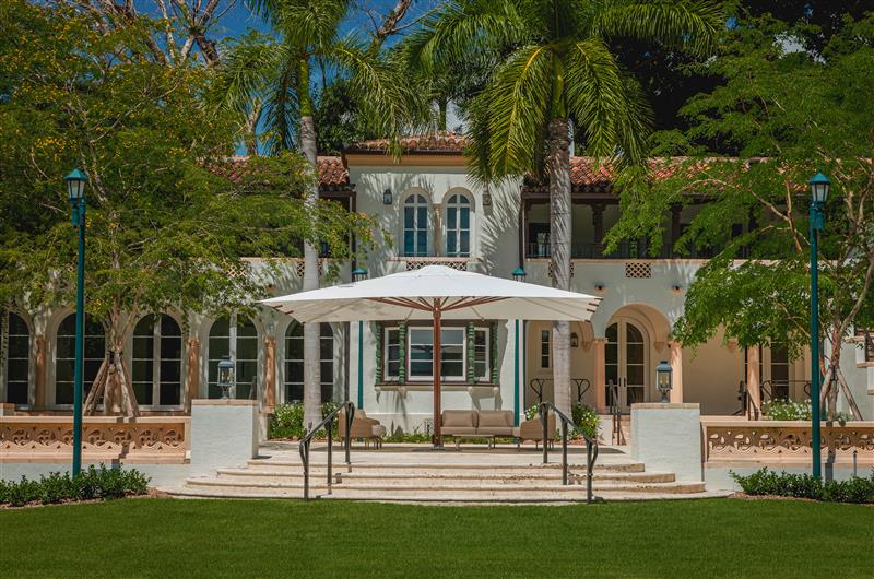 Large parasol on veranda in front of palatial Spanish-style home