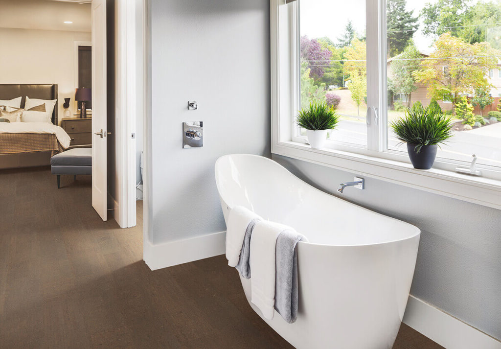 Amorim Wise cork floor medium brown tone that looks like wood in bathroom with large slipper-shaped tub
