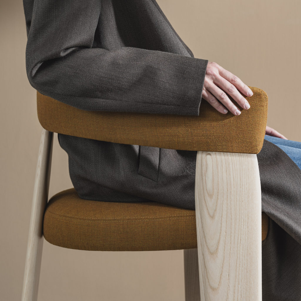 side view Oru chair with seated person, brown upholstery