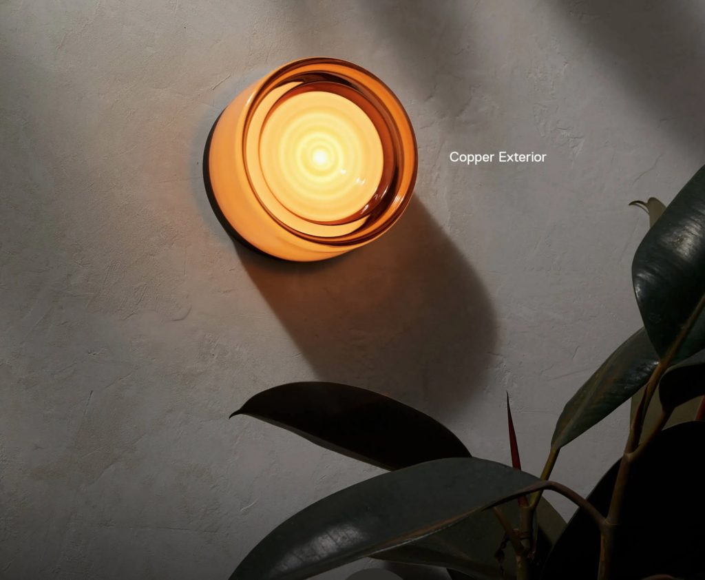 Scone with Copper colored diffuser on wall with plant