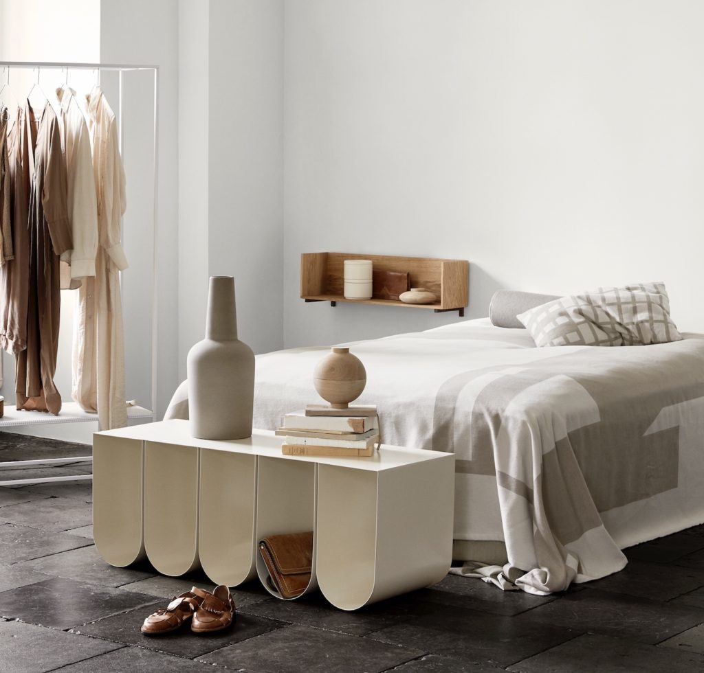 Curved bench in white in front of bed