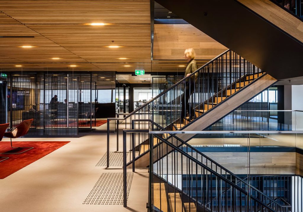 Blade ceiling tiles in split-level workspace with woman walking down the stairs