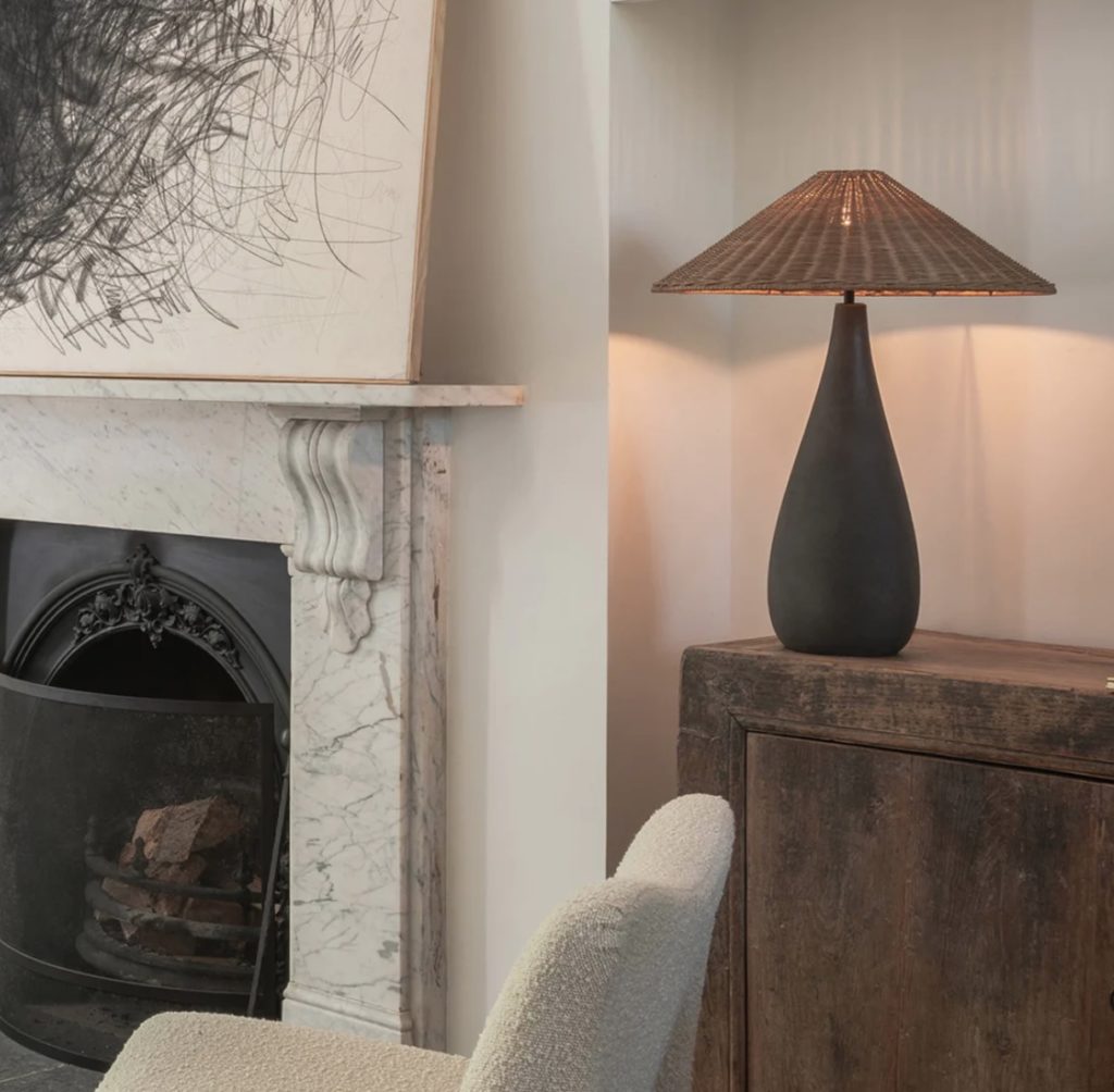 Miata table lamp with concrete base and rattan shade in living room near fireplace