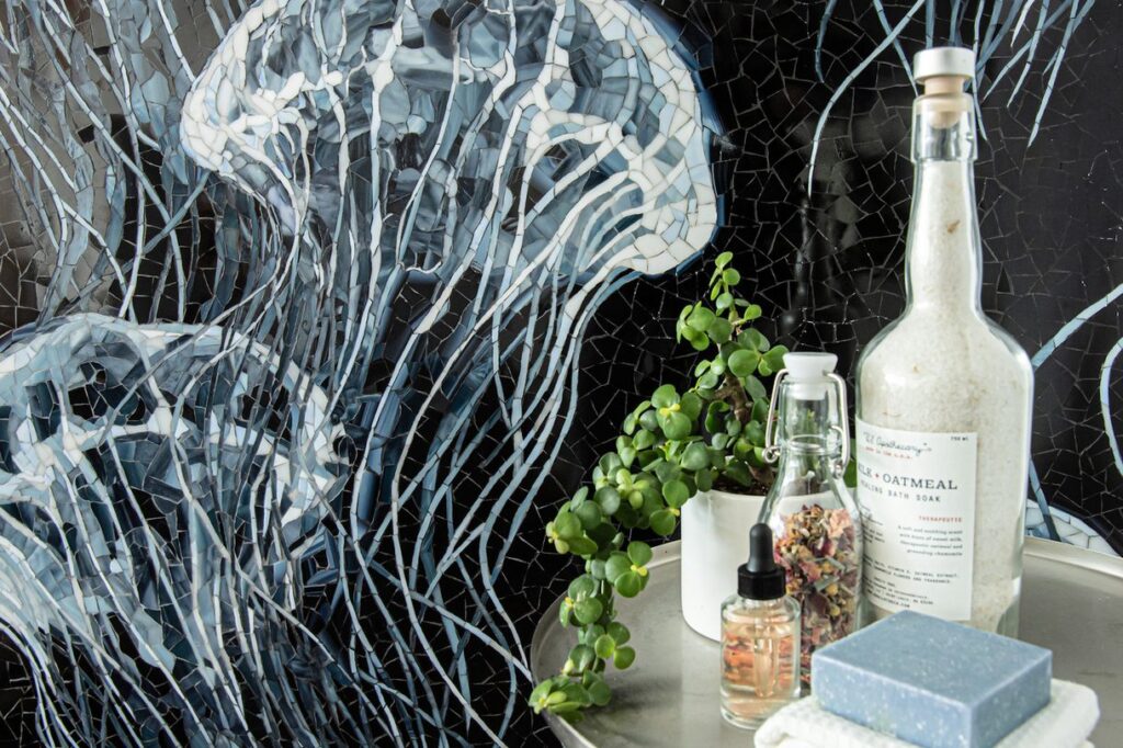 Moon Jellies mosaic of jellyfish on black background with tray of bath products next to it