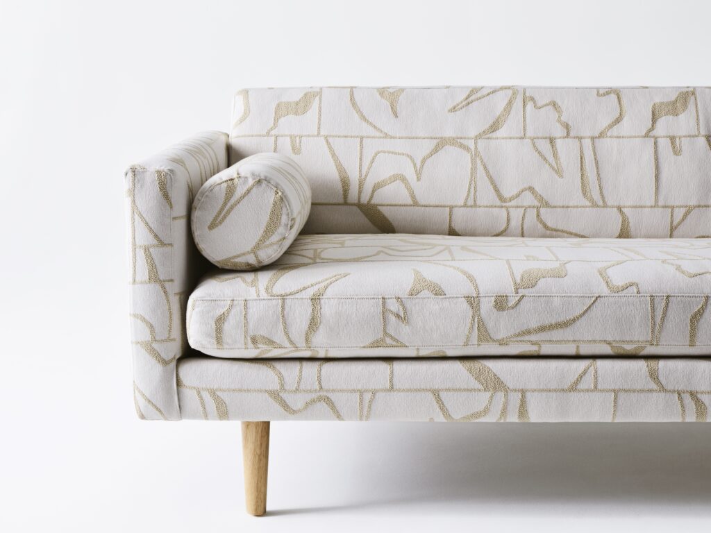 Endeavor collection dance floor fabric with white base and gold squiggles on couch