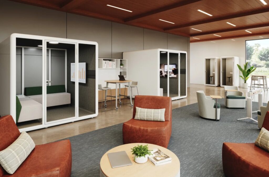 Kolo pods in white, two pods with freestanding table between them in open office with orange chairs and low table in foreground