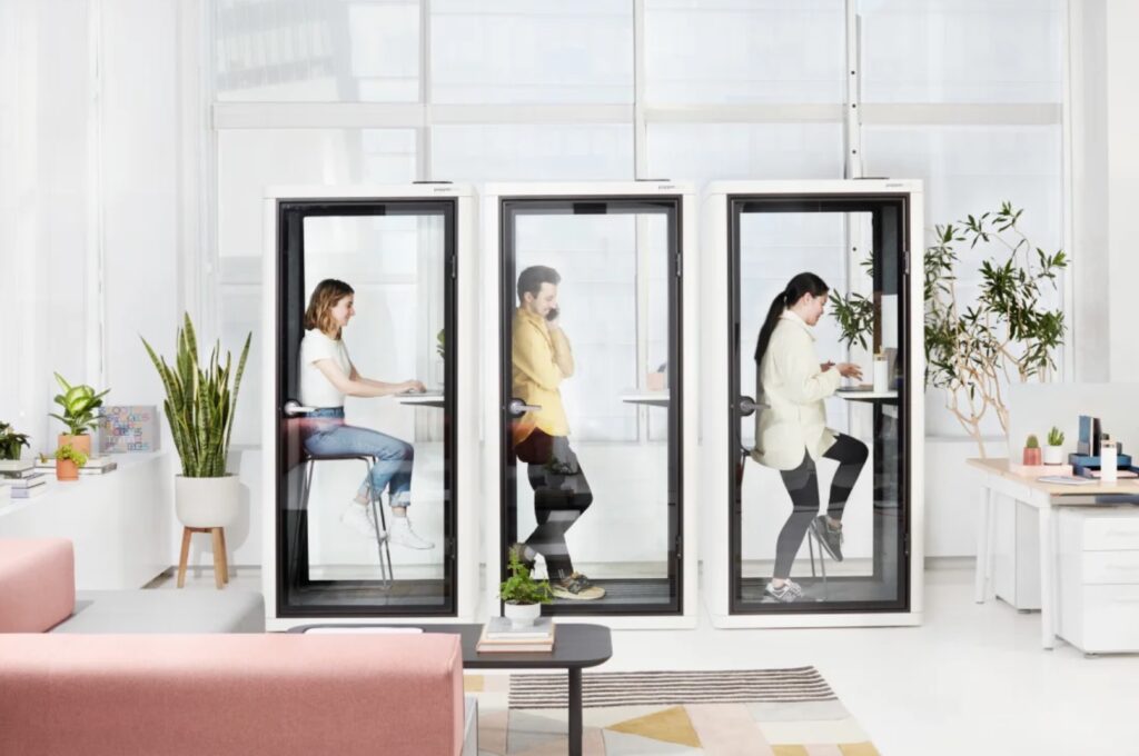 Om pods three in a row with white trim and people inside working or talking