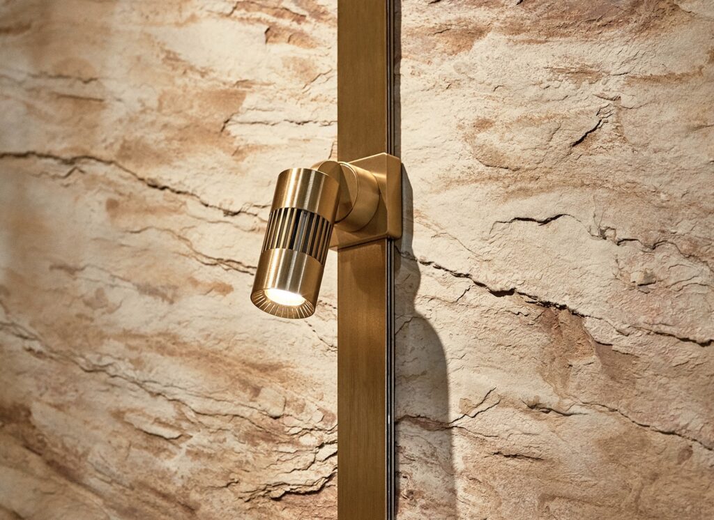 Light node in brass finish against sandstone rock wall