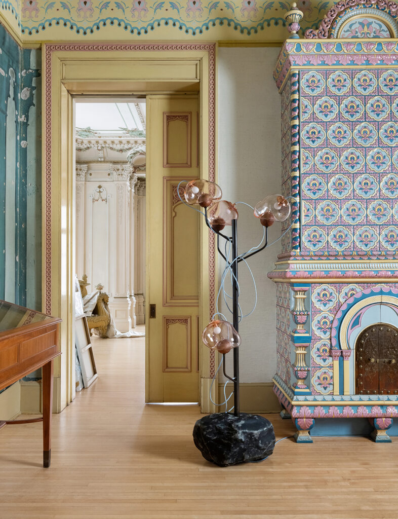 Ontologia floor lamp with pink transparent shades in front of colorful Swedish style chimney
