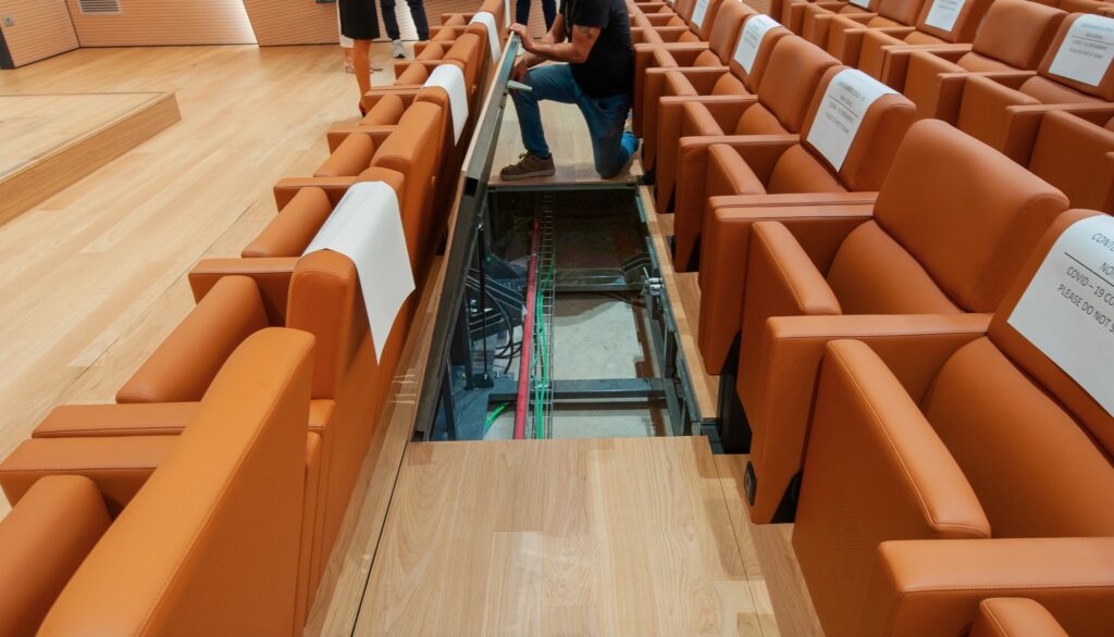 Auditorium with wood floor section removed to access electronics