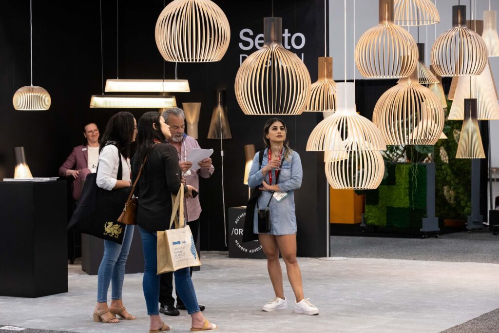 Exhibitor lighting booth with people milling beneath fancy pendant lights