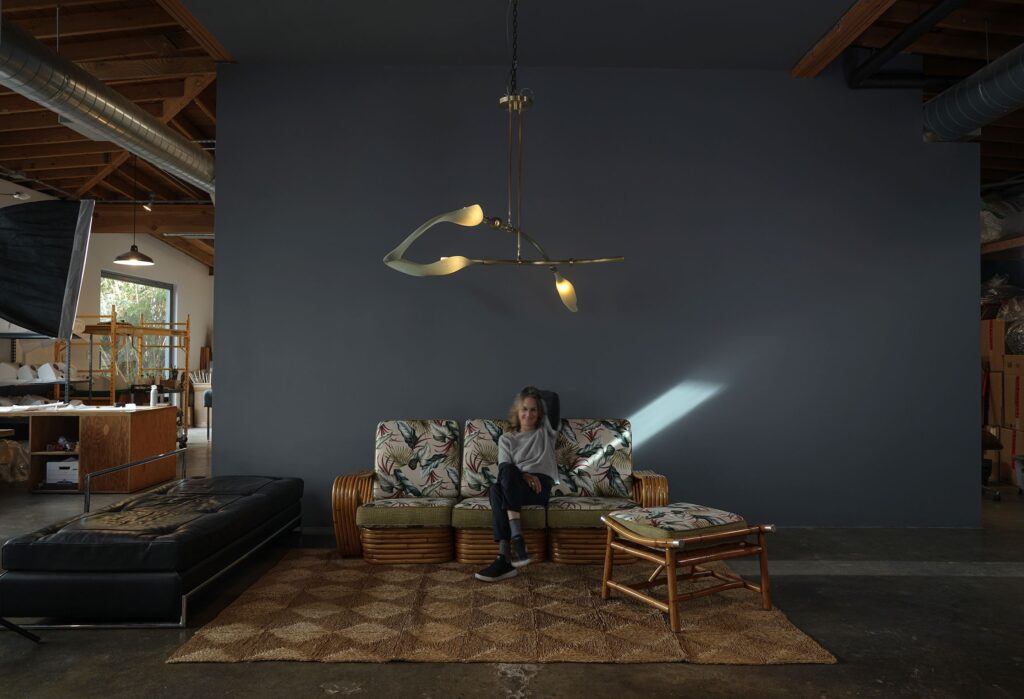 Andrea Claire on sofa in room with Pisces chandelier overhead
