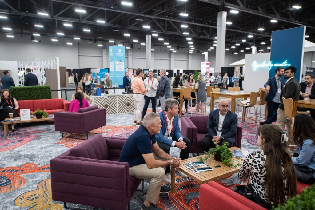 HD Expo lounge area with purple and pink chairs and people relaxing and talking