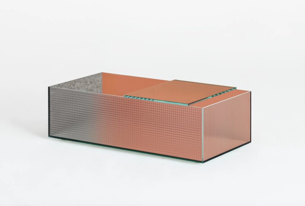 glass table with orange colored glass and one side covered in gray fabric