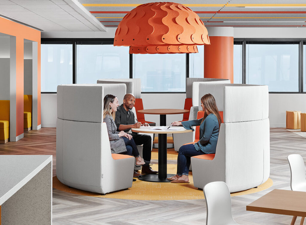 Bota booth in light gray beneath big orange light fixture with people working