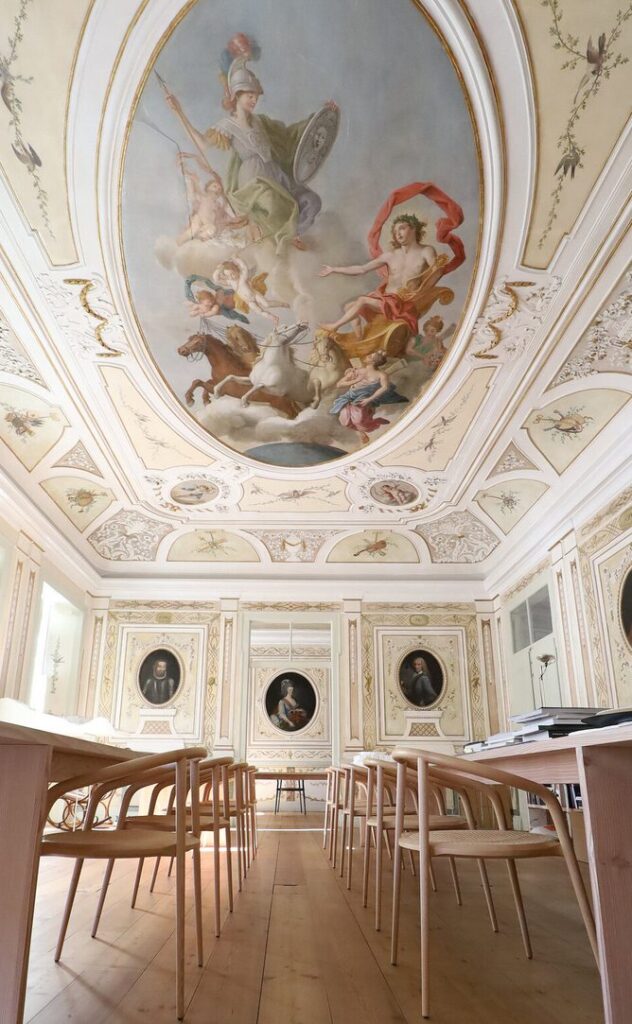 Many chairs in natural at long tables in museum like palace with Neoclassical vibe