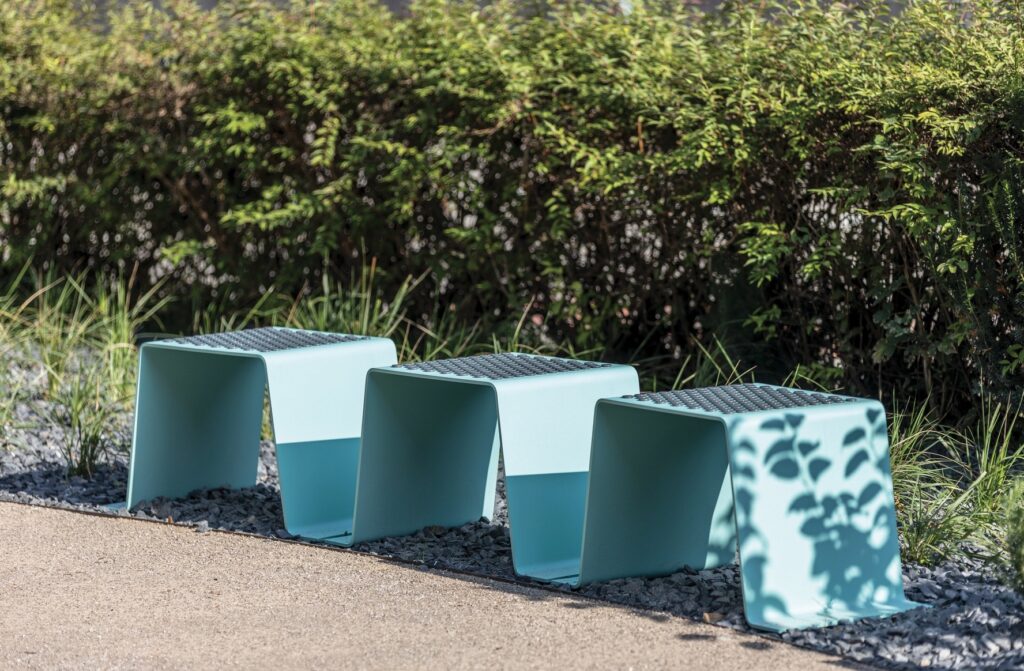 Sinus bench in light blue with hedges nearby