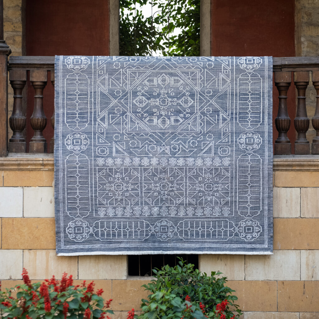 Kilim rug with intricae pattern in light blue/white draped over banister