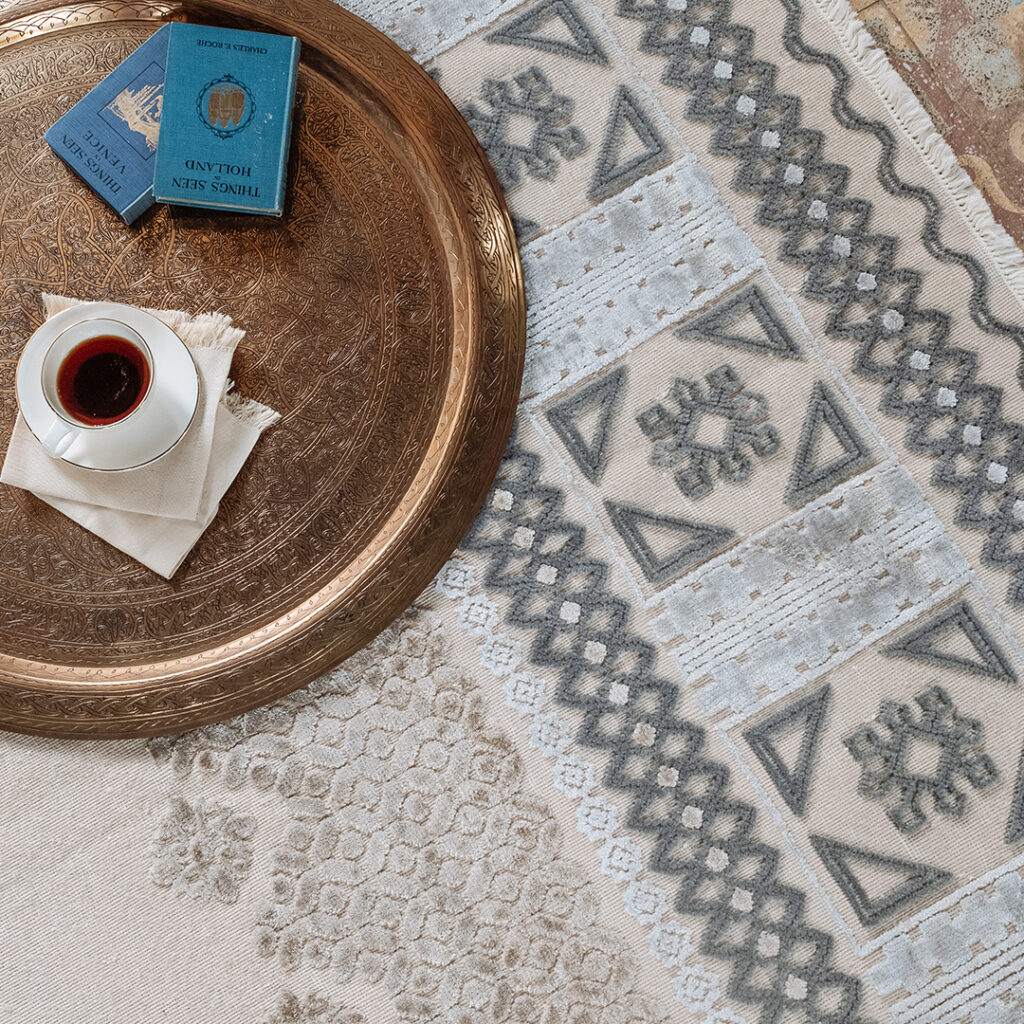 Kiliim rug detail white background with designs in gray, cream, light blue