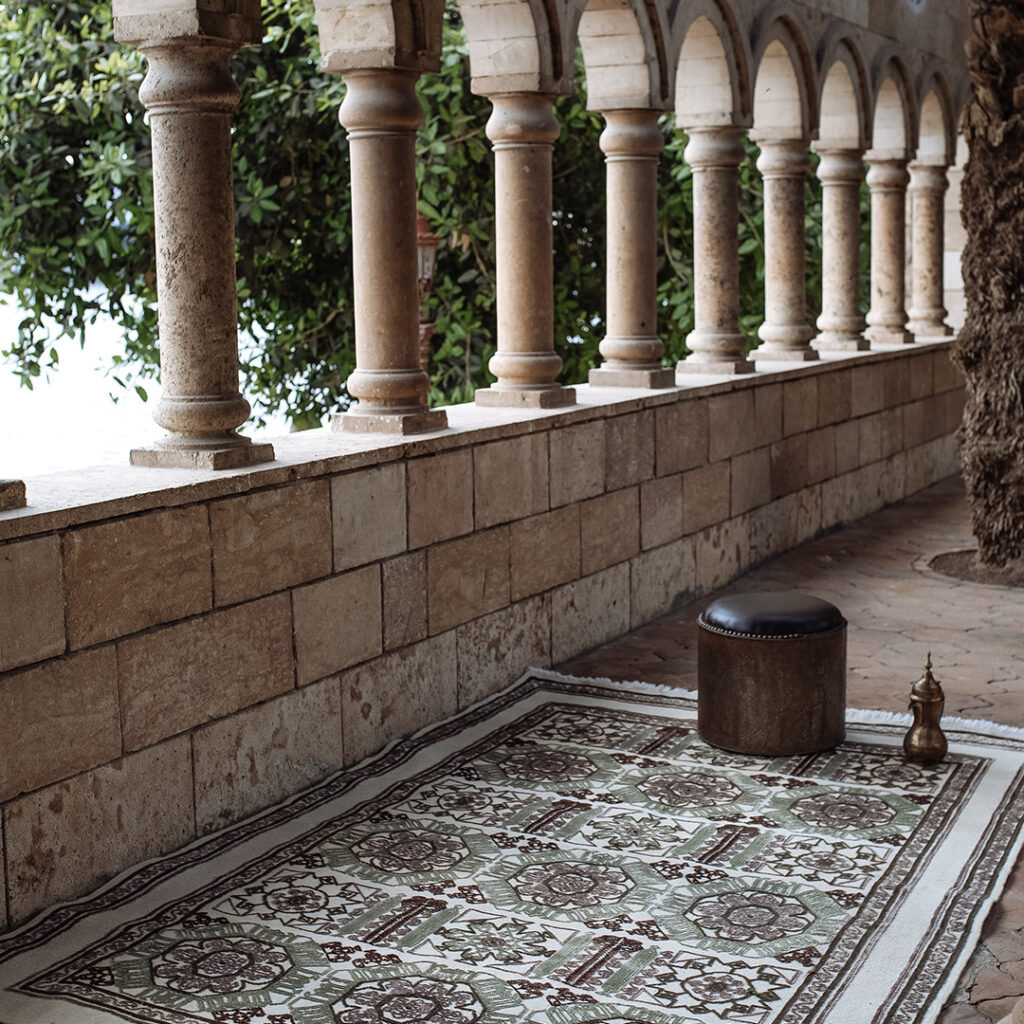 Kiliim rug with geometric pattern on floor of patio with intricate stone and tile work