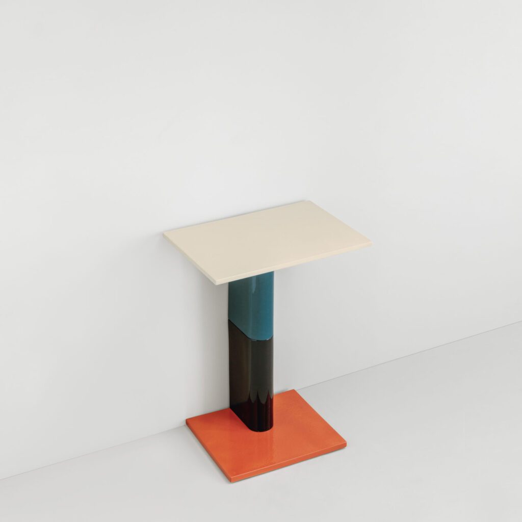 wall-mounted table with orange base, green/black shaft, and white top