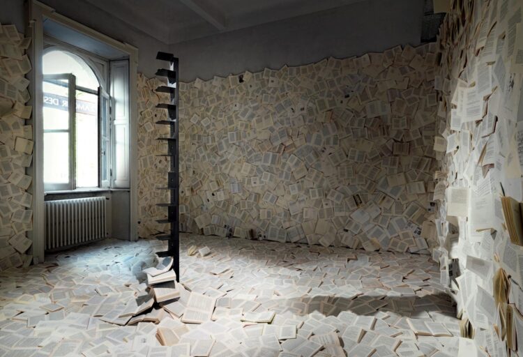 Ptolomeo bookcase in black surrounded by books all over the floor and walls
