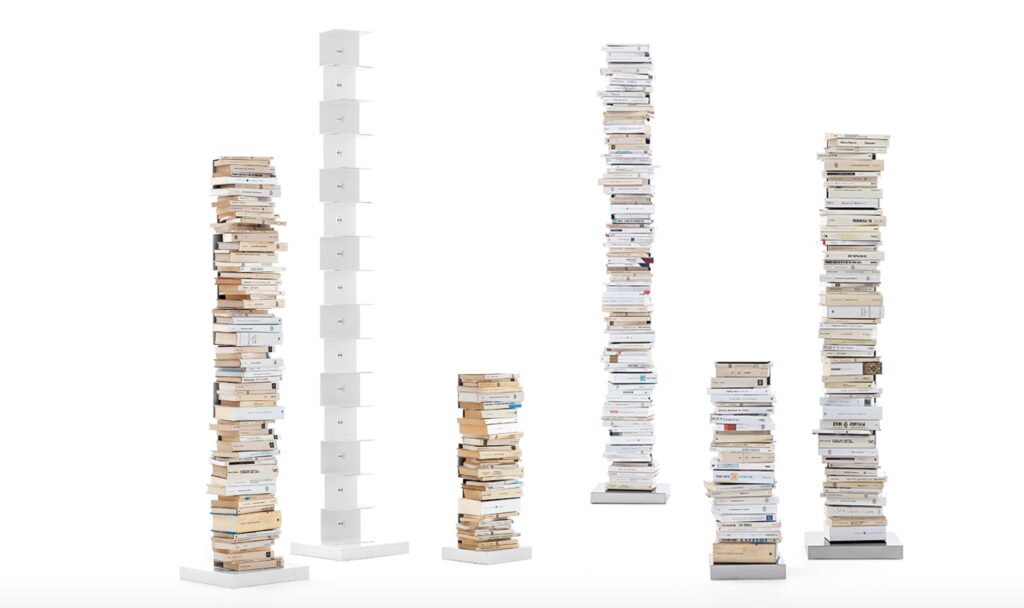Several freestanding bookcases: five full of books and one empty