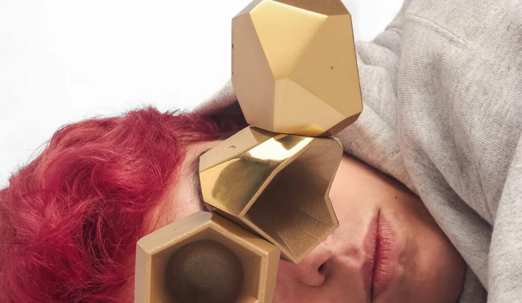 Brass cups balanced in front of person lying on their side