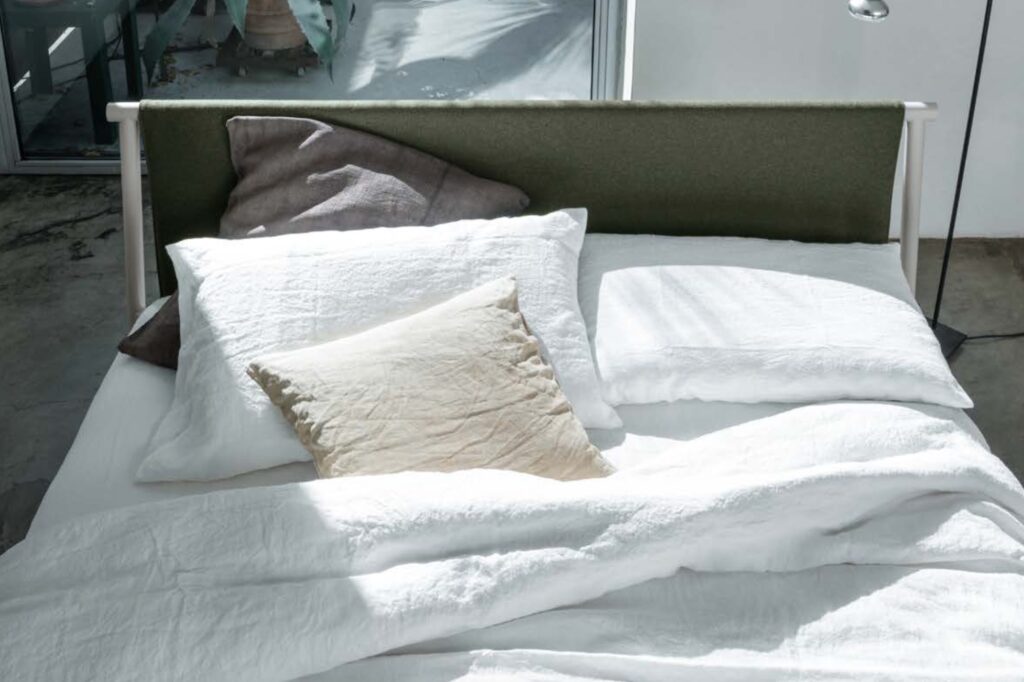 Bed with white linens and green fabric headboard