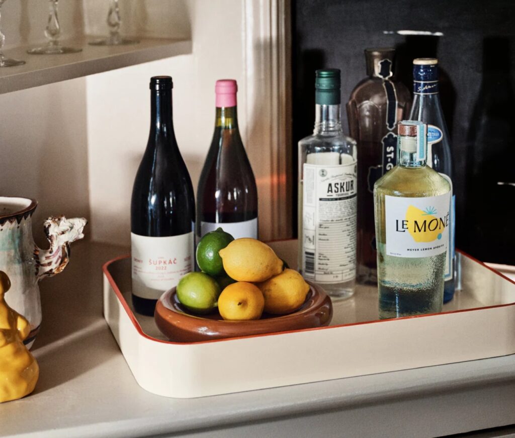 Sonia lacquer tray in cream with alcohol bottles and a bowl of lemons and limes