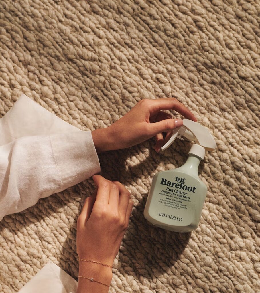 Armadillo bottle with eucalyptus. Hands and rug. 
